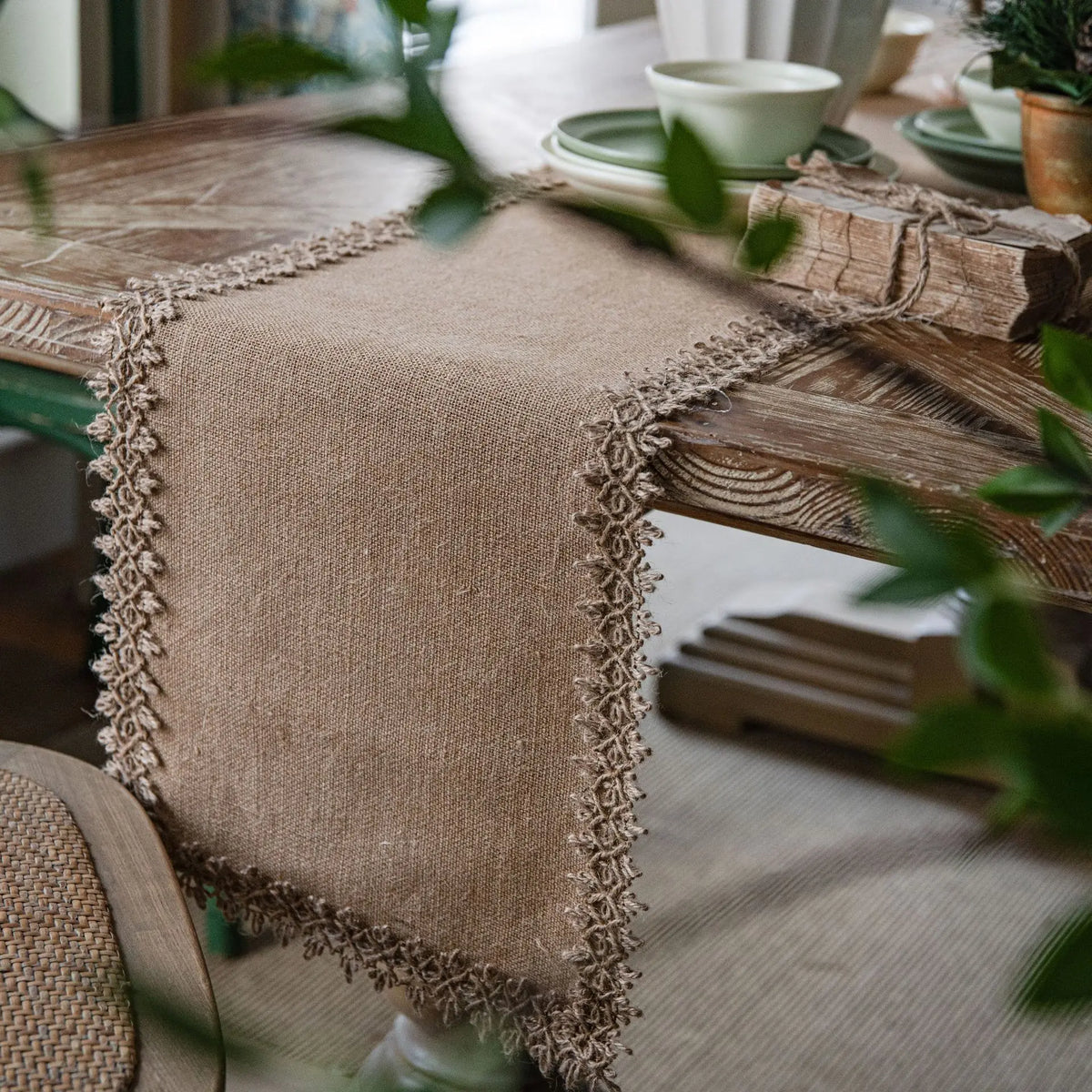 Natural jute table runner with intricate lace edge on rustic dining table