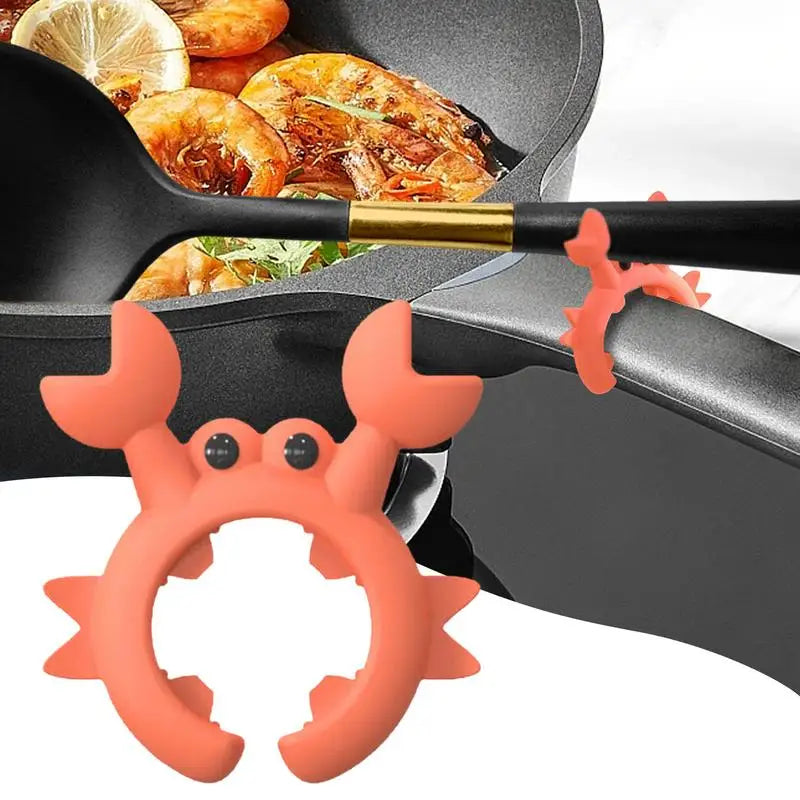 Crab-shaped silicone utensil rest holding a spoon on a black pot handle with food cooking in the background
