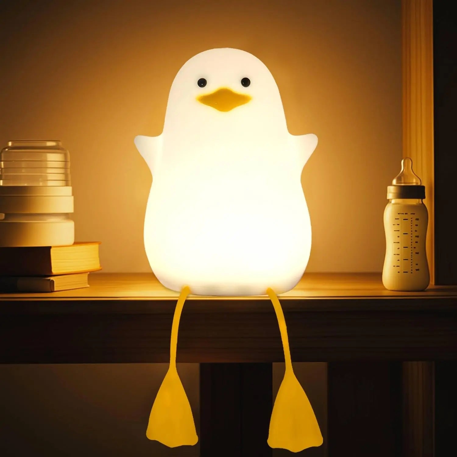 Soft silicone duck night light glowing on a bedside table with a baby bottle and books