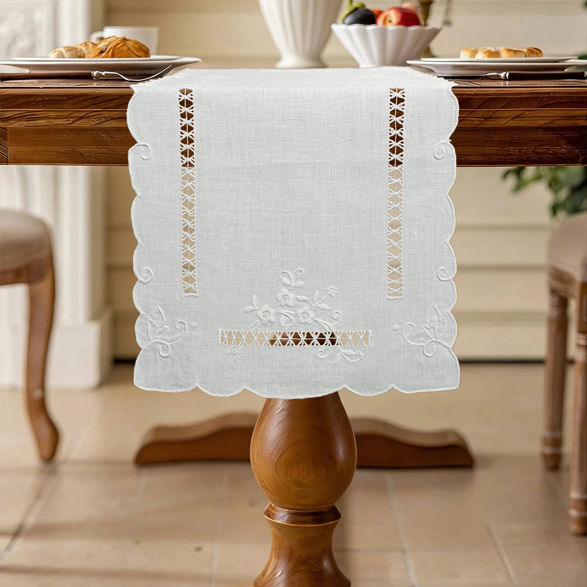 Embroidered linen table runner with scalloped edge styled on a wooden dining table