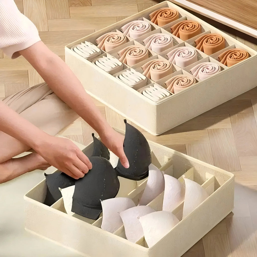 Person placing bras into khaki fabric compartment organizers on a wood floor