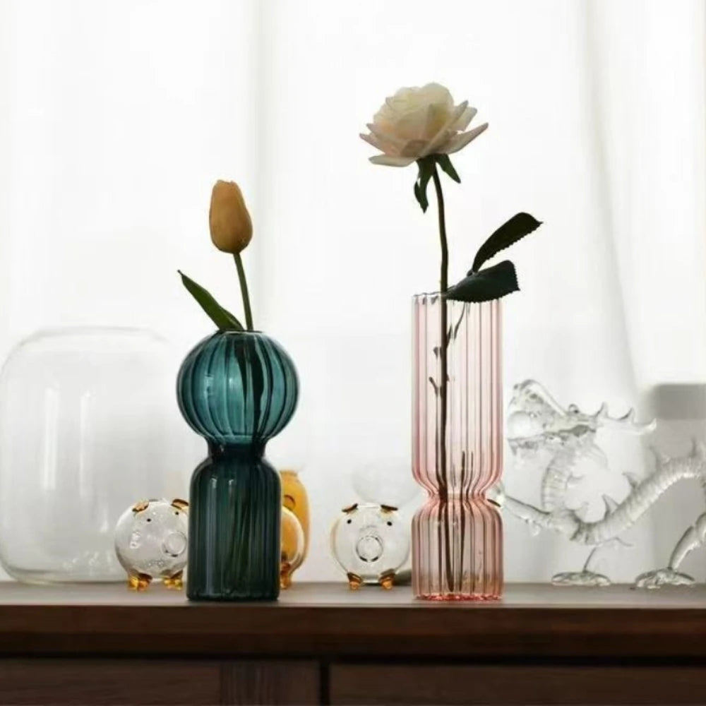 Teal and pink striped glass vases on a shelf with decorative glass animal figurines