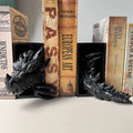 Black dragon head and tail resin bookends holding books on a shelf