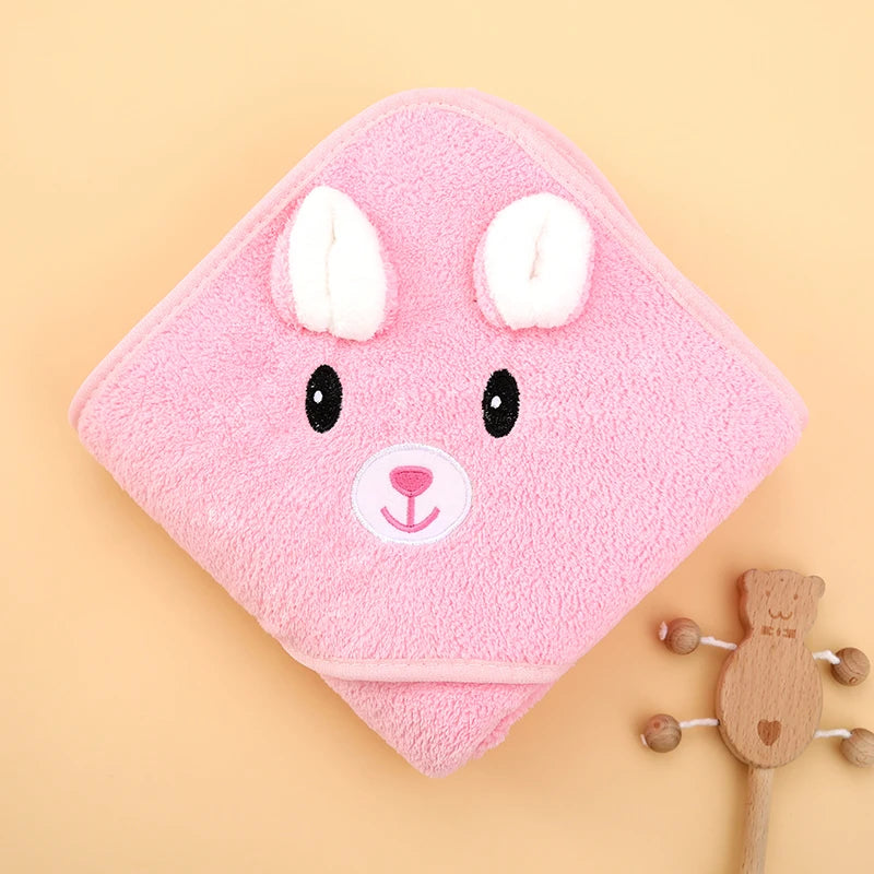 Folded pink rabbit hooded baby towel with ear details on a neutral background