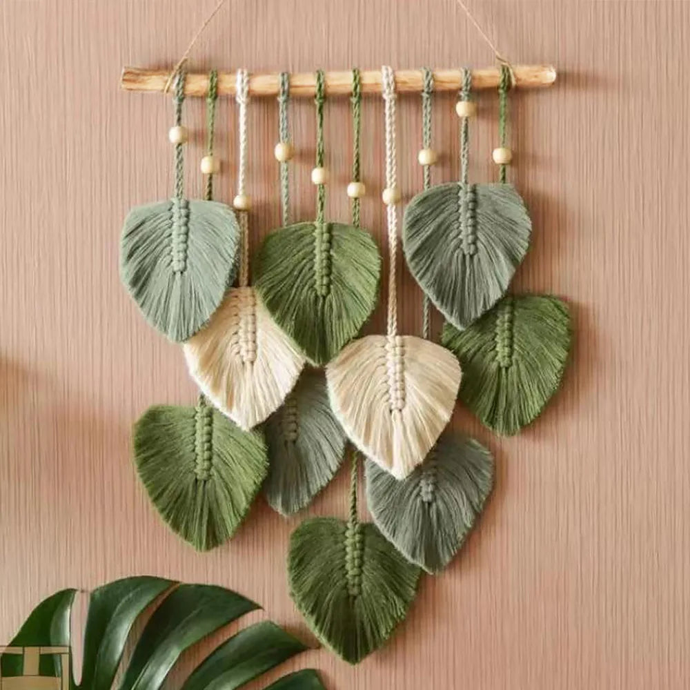 Green and cream woven leaf tapestry wall hanging on light wood background