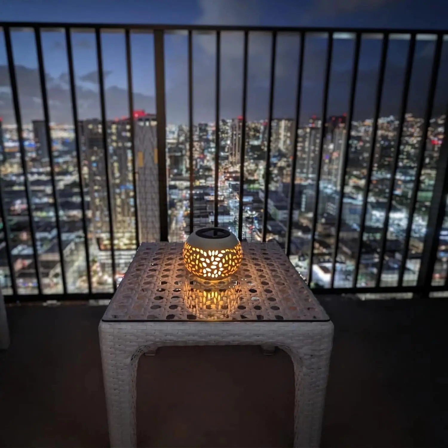 Solar table lantern on a balcony table overlooking a city at night