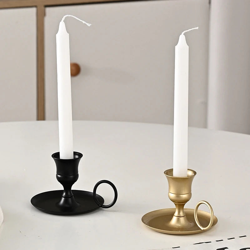 Black and gold chamberstick candle holders with white taper candles on a tabletop in a home setting