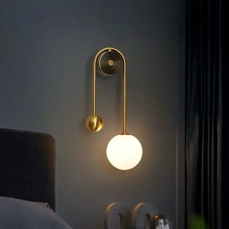 Single gold globe wall sconce with frosted glass shade on a dark blue bedroom wall
