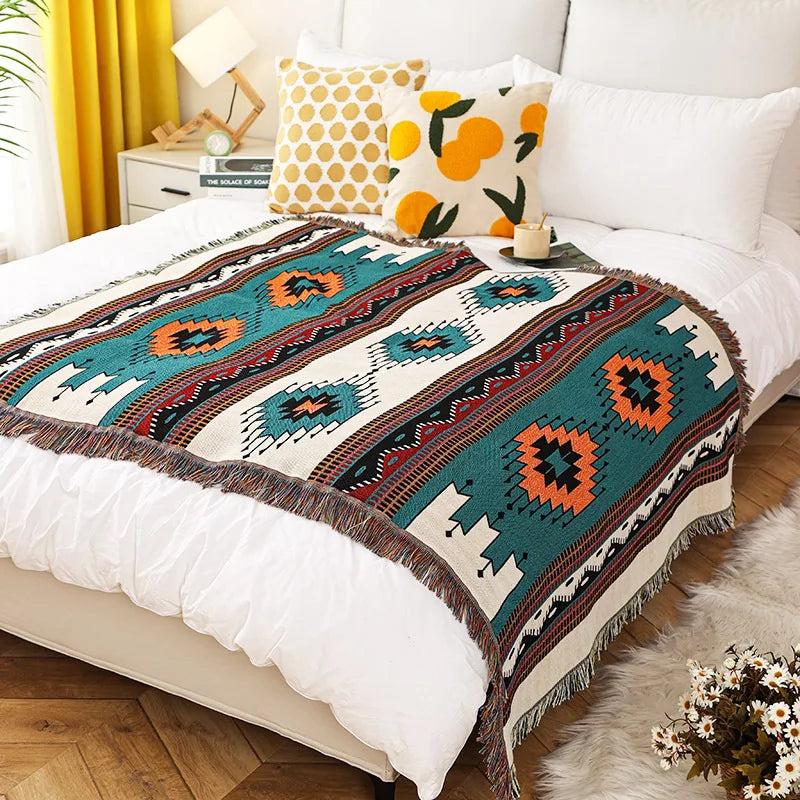 Blue and orange geometric throw blanket laid out on a bed in a sunny bedroom