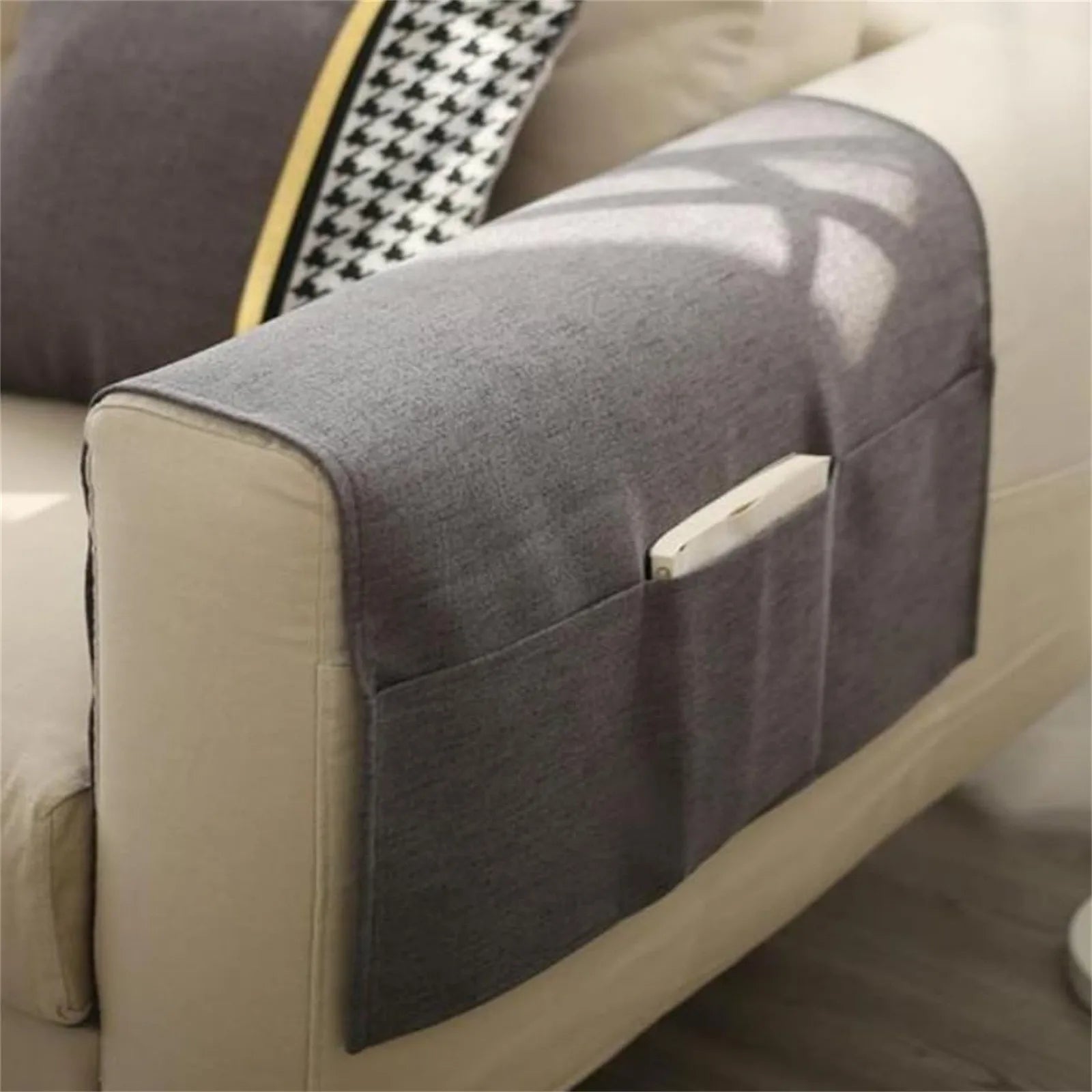 Gray fabric sofa armrest organizer with pockets on beige sofa, remote stored in pocket