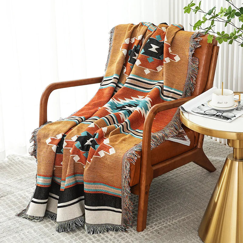 Woven geometric throw blanket over a wooden armchair with a gold side table, natural light