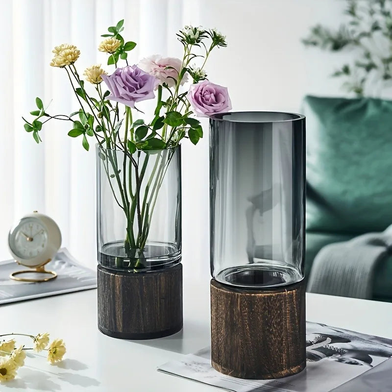 Pair of cylinder glass and wood vases, one holding pastel flowers, on a white table