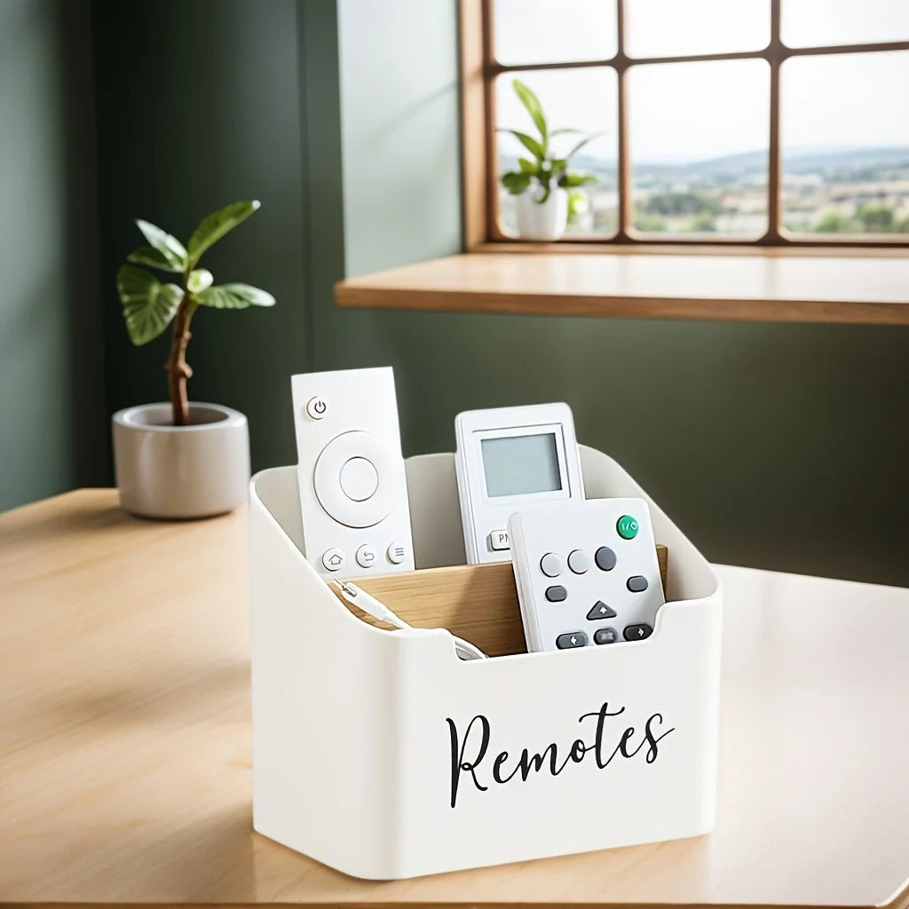 White remote control holder caddy with two compartments on a table, holding various remote controls