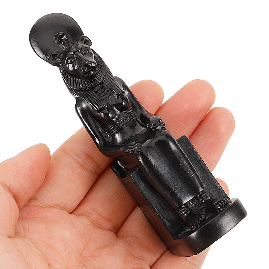 Hand holding small Egyptian goddess figurine, demonstrating compact size