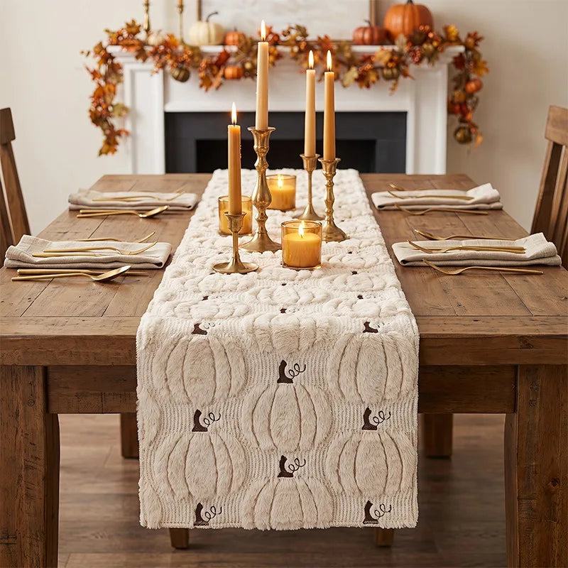 Beige pumpkin table runner on rustic dining table with gold candlesticks and neutral napkins