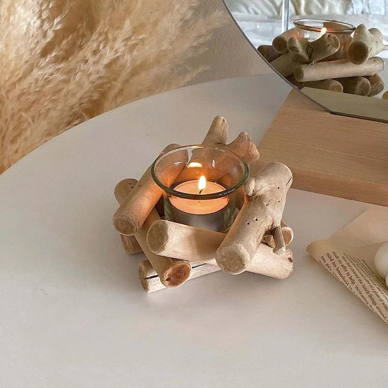 Driftwood candle holder with glass cup on a round table, lit candle inside