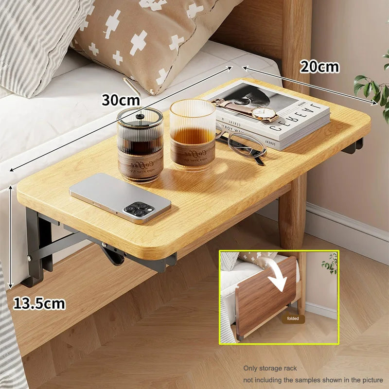 Foldable clip-on bedside shelf in light yellow attached to bed frame, measurements labeled