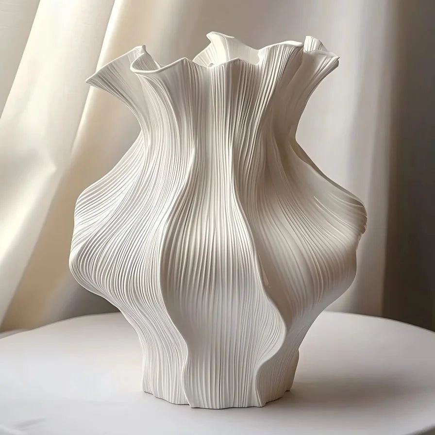 textured ceramic wave vase in white shown on a tabletop with soft curtain background