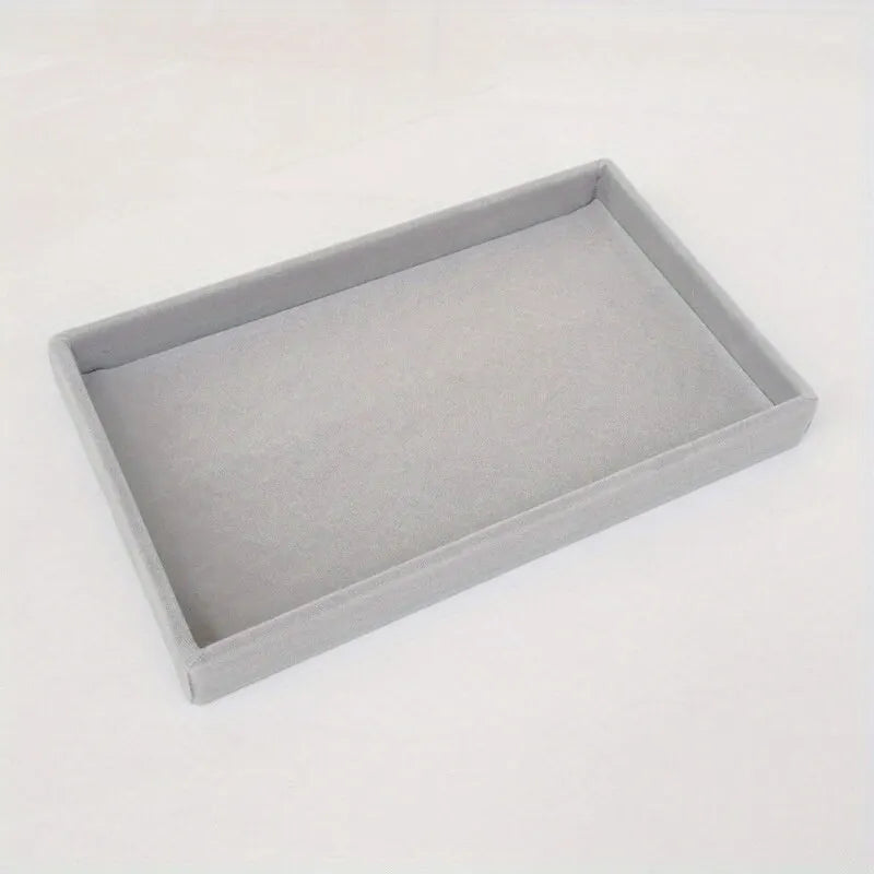 Simple open grey velvet jewelry tray, empty, on white surface