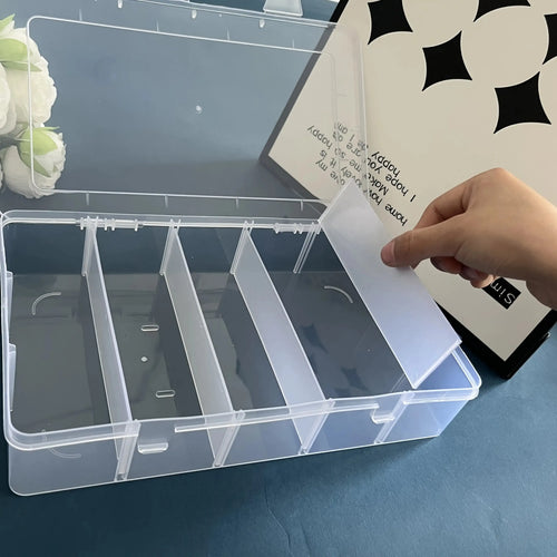 Person adjusting removable divider in empty clear organizer box on blue table