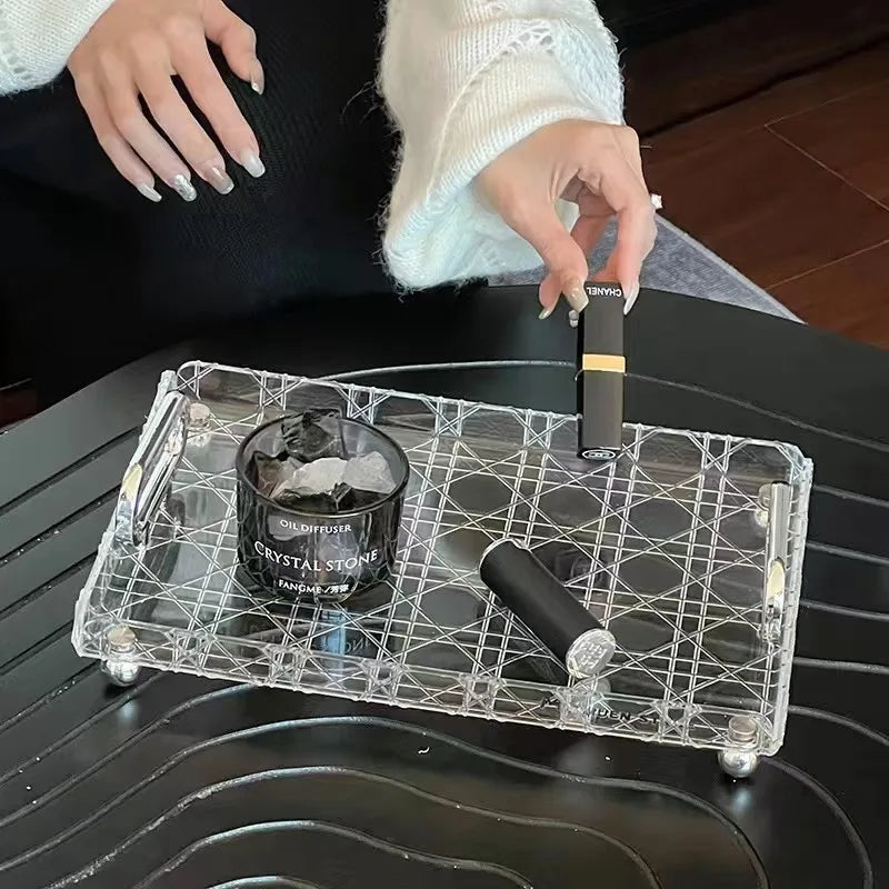 Transparent geometric tray used as a coffee table organizer with candle and makeup
