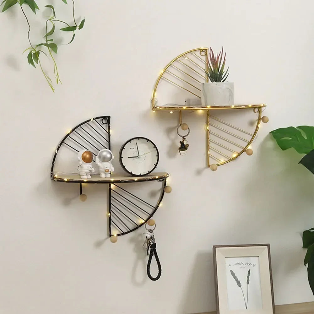 Pair of semi-circular wall shelves in black and gold with decor and accessories, mounted above a desk in a living area.
