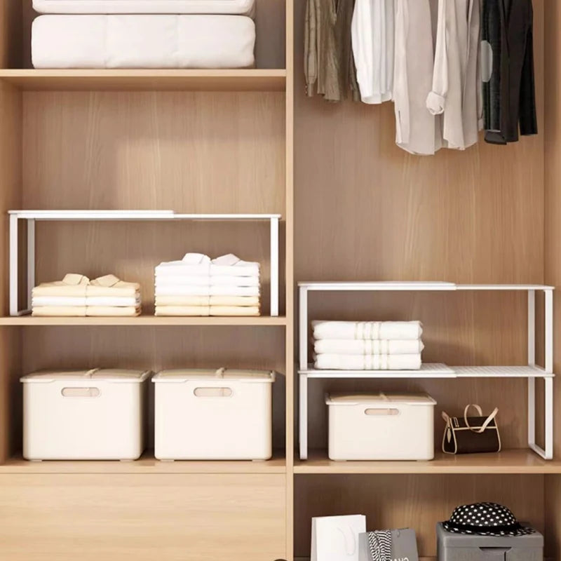 Two adjustable closet shelf organizers placed in a wooden wardrobe, holding folded towels and storage bins
