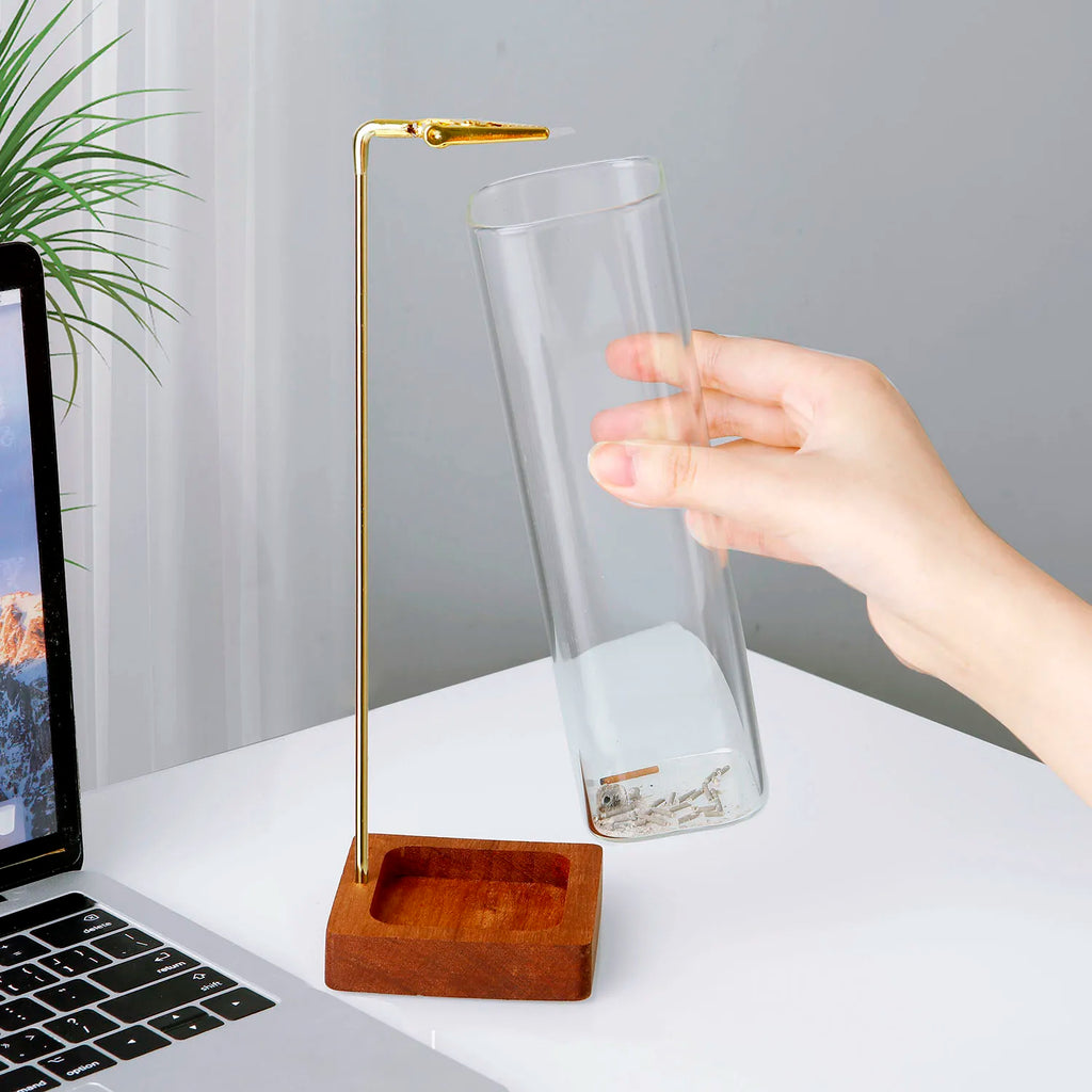 Hand removing the glass cylinder ash catcher from the wooden incense holder base