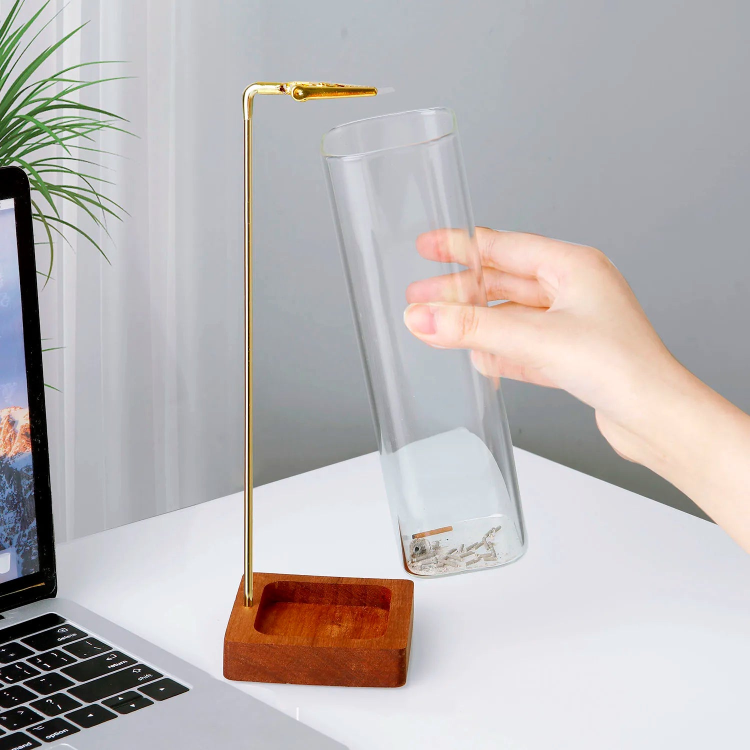 Hand removing the glass cylinder ash catcher from the wooden incense holder base