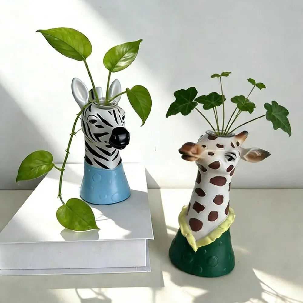 Zebra and giraffe pottery vases styled on a white surface with leaves