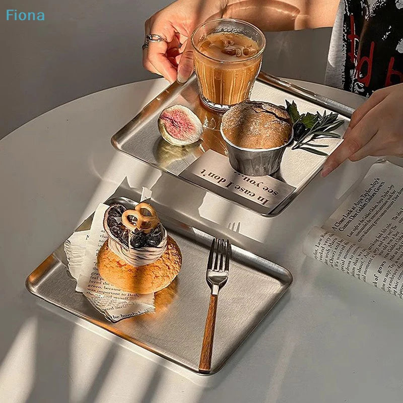 Coffee and snacks served on stainless steel trays in a cozy home setting with sunlight
