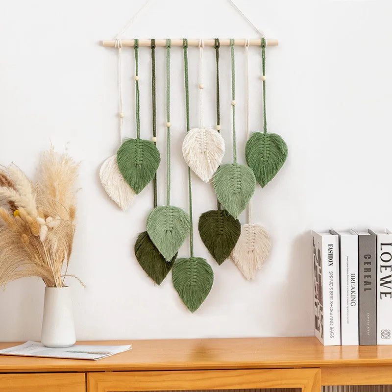 Leaf macrame wall hanging in green and cream colors above a wooden console