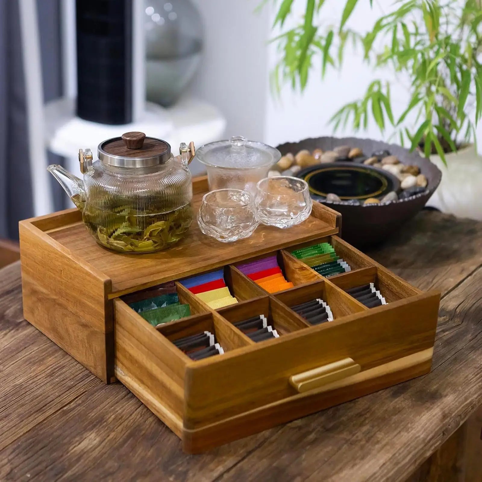 Wood tea bag organizer box with glass teapot and cups on a dining table