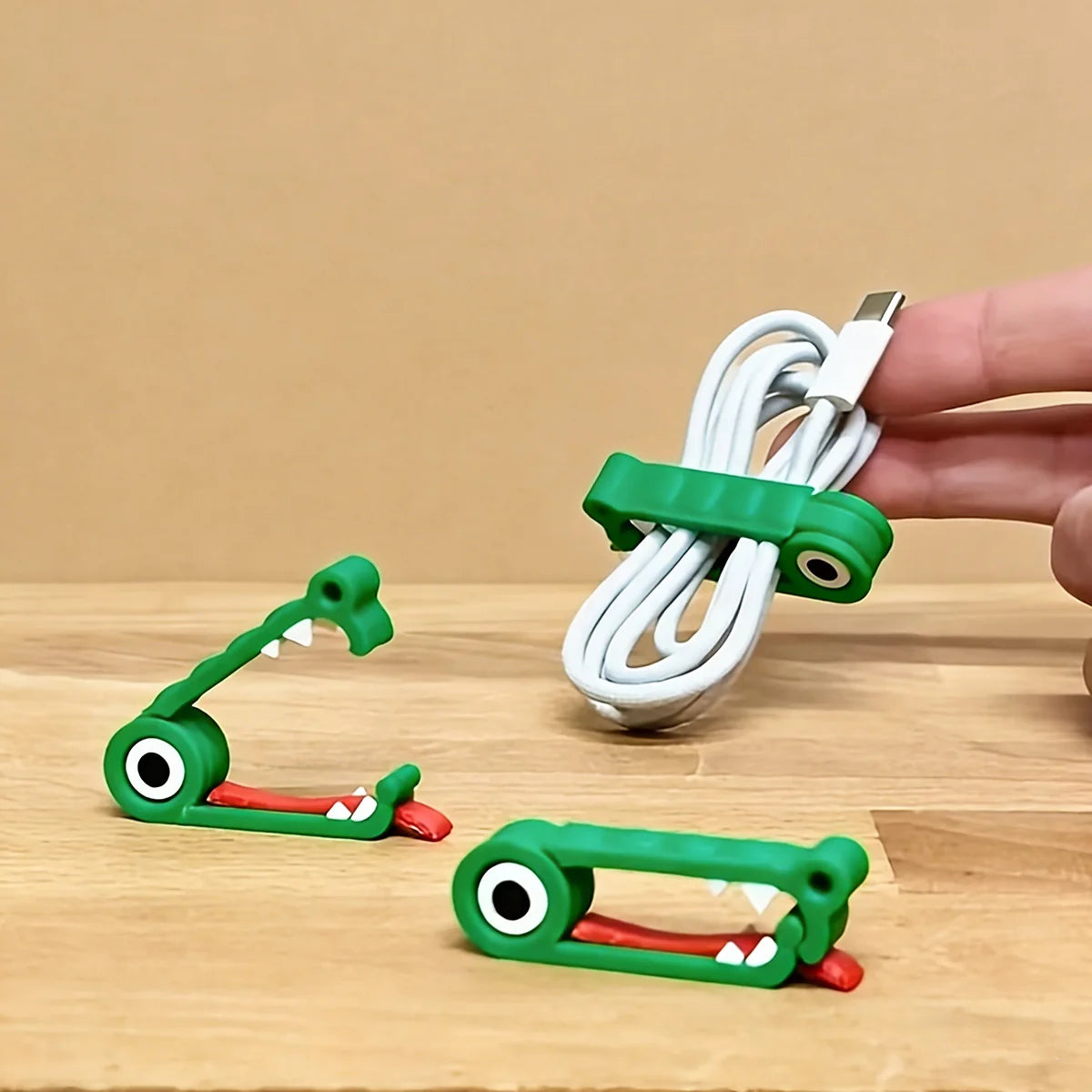 Crocodile cable clips on a wood table, hand holding a clipped charging cable