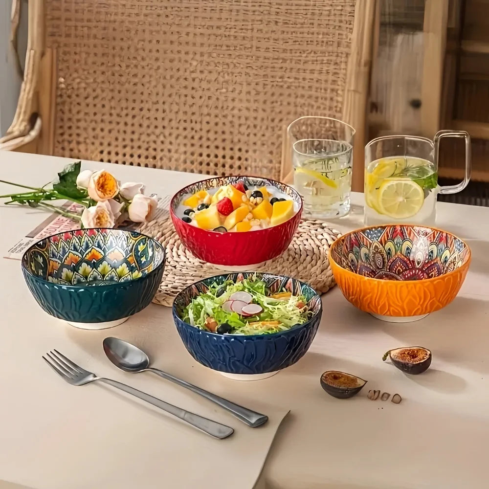Set of four Bohemian patterned bowls on a table with salad and fruit, showing colorful interiors and exteriors