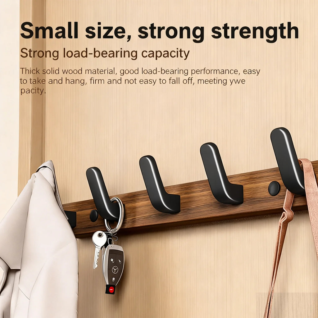 Wall-mounted wood and metal coat rack with four hooks on a wooden wall, holding keys, a coat, and a bag with visible product text