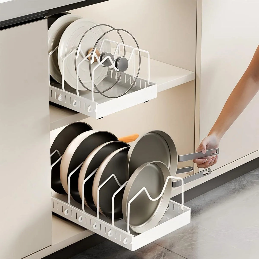 White pull-out drawer organizer with pans and lids in a kitchen cabinet