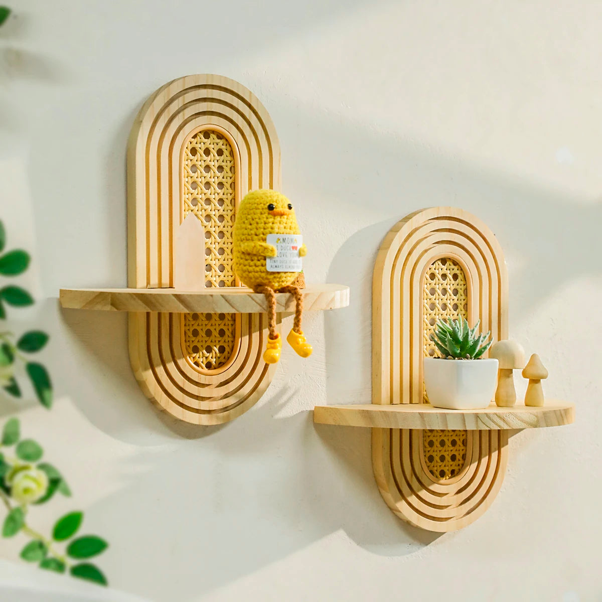 two arched wooden floating shelves with rattan inlay mounted on a wall, each styled with small decor items
