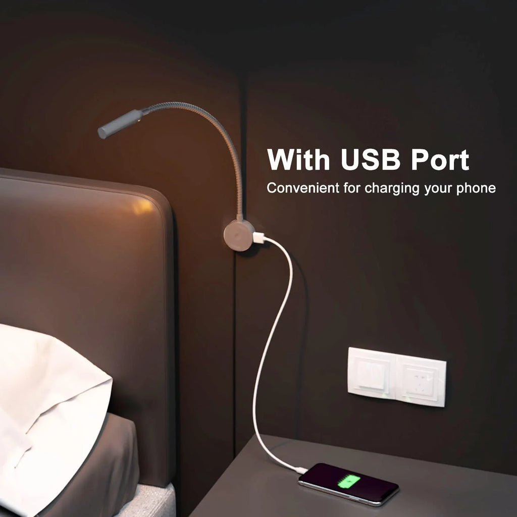 Black wall mounted reading lamp above a bed, showing USB port in use with phone charging at a bedside nightstand
