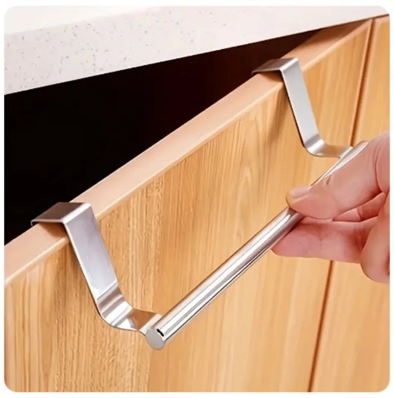 Close-up of a silver stainless steel over-cabinet towel bar being installed on a wood cabinet door