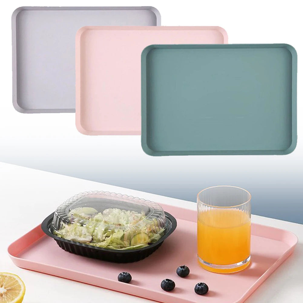 Matte plastic trays in pink, gray-purple, and green displayed; pink tray shown serving salad and juice with blueberries.