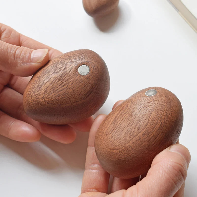 Close-up of hands holding two stone-shaped wooden pieces with magnets