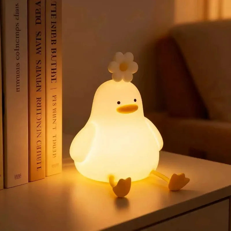 Duck shaped silicone night light on a nightstand beside books
