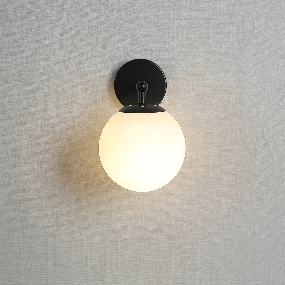 Front view of globe wall sconce with black finish and frosted glass shade
