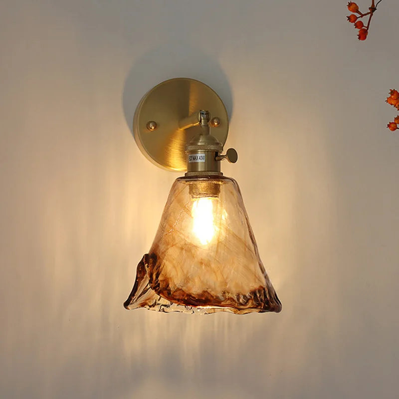 Amber glass wall sconce in bell shape with brass mounting plate and cozy lighting effect