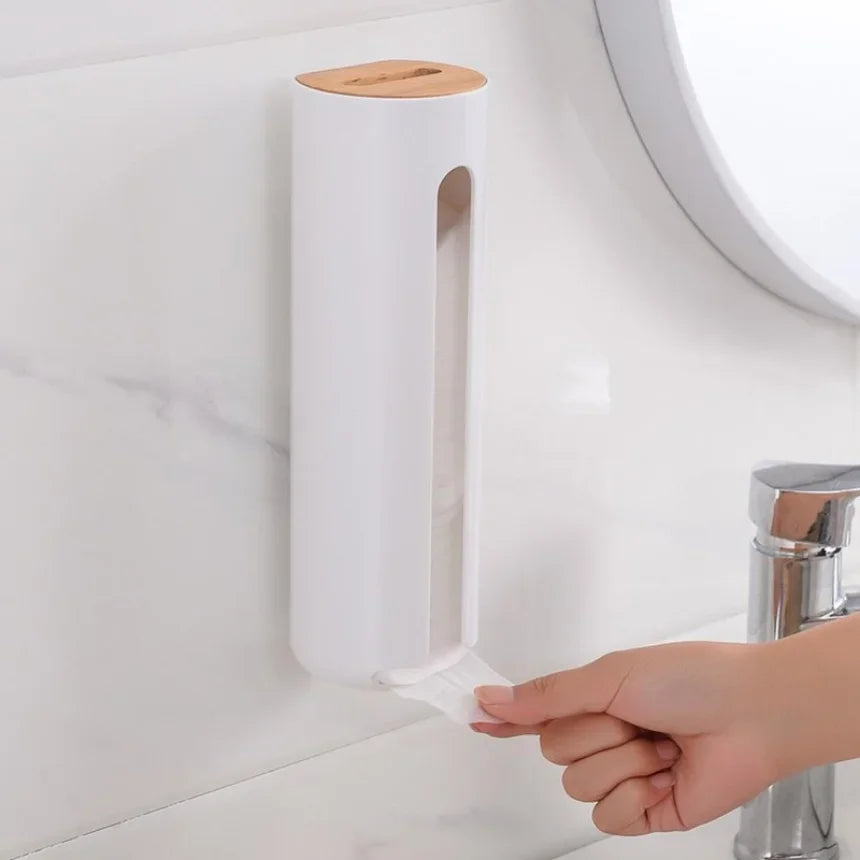Hand pulling a cotton pad from a white wall-mounted cotton pad holder with wood top in a bathroom setting