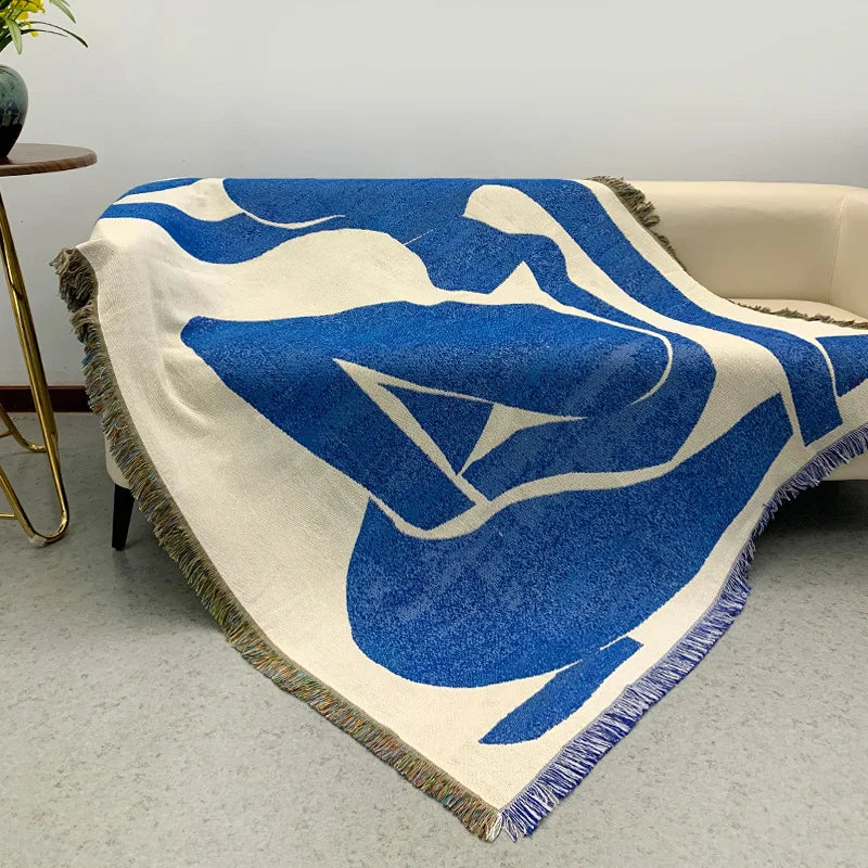 Abstract woven throw blanket with blue geometric figure draped over sofa