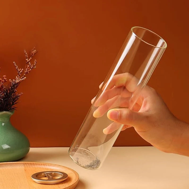Hand holding clear glass body of incense burner with removable lid shown nearby