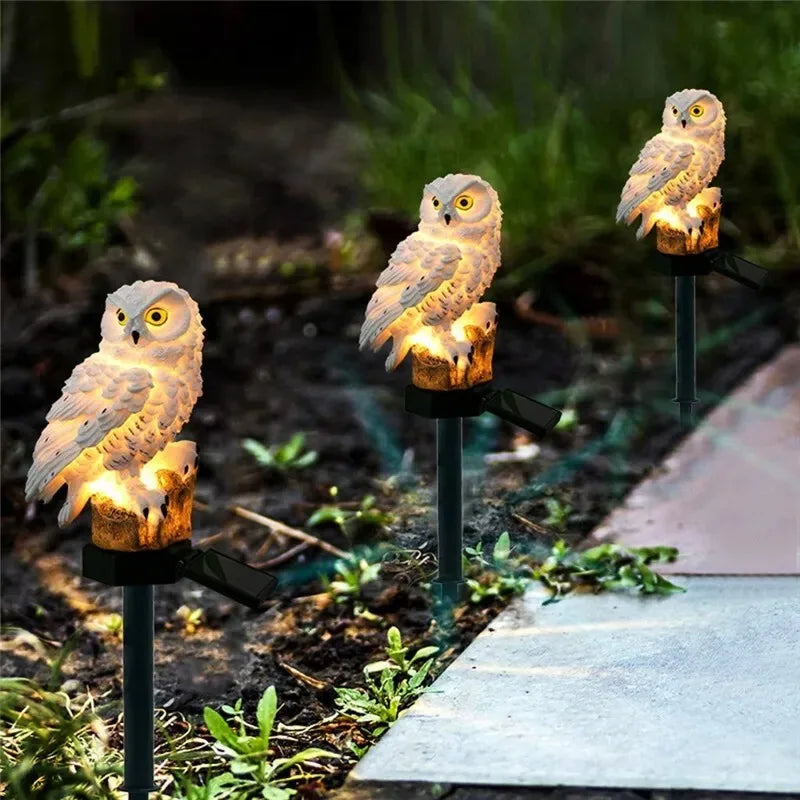 Row of white owl solar stake lights lining a garden pathway at dusk