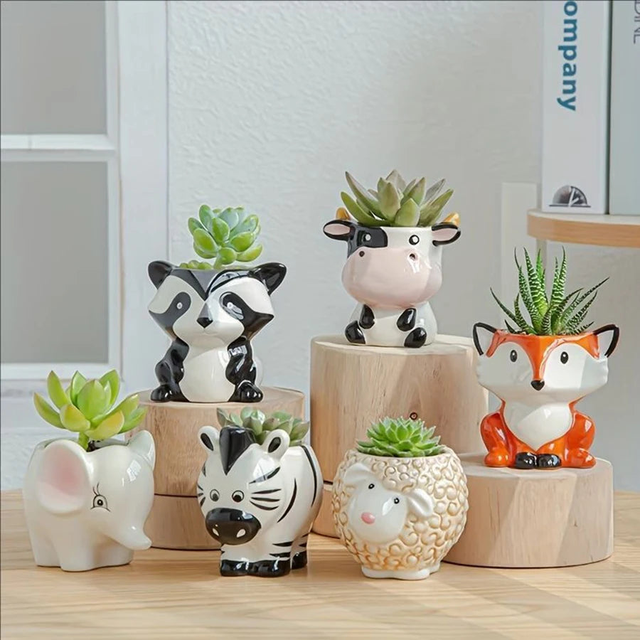 Six small porcelain animal-shaped ceramic planters holding succulents on a wood table